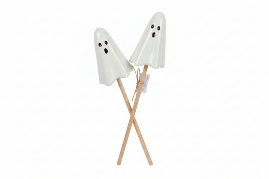 Two white ghost-shaped decorative objects with black eyes and mouths, mounted on crossed light wood sticks, shown against a plain white background.