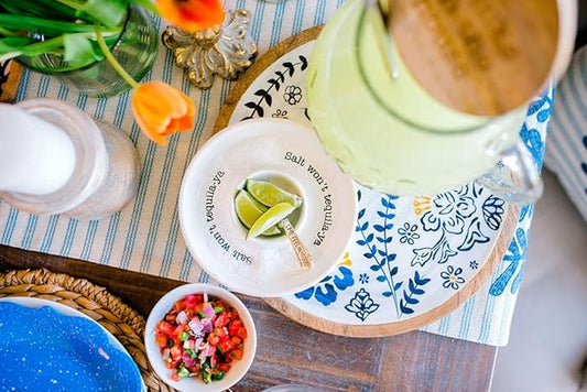 A white ceramic dipping bowl with black printed text reading 'Salt won't tequila-ya' around the rim, featuring a silver fork resting inside.