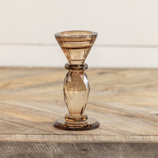 Amber glass candle holder on a wooden surface with a neutral background