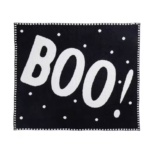 Black blanket with white 'BOO!' text and polka dots on a white background