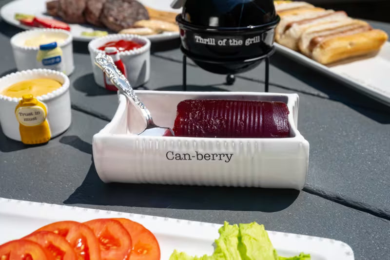 2-piece Cranberry serving dish set  with serving dish and spatula. Cranberry serving dish features debossed sentiment that reads "Can-berry". vintage style spatula reads "slice n' serve". BBQ summer scene.