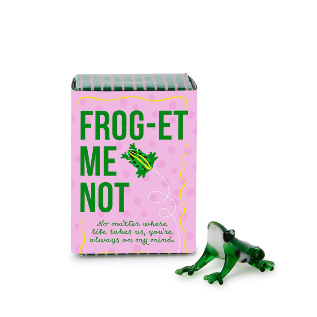 Frog figurine with a pink box labeled 'FROG-ET ME NOT' on a white background