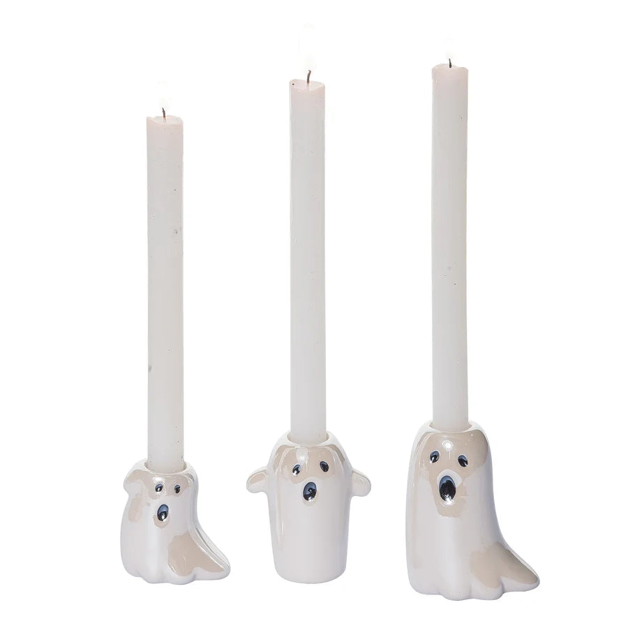 Three white taper candles in ghost-shaped holders with painted faces, shown on a plain white background.