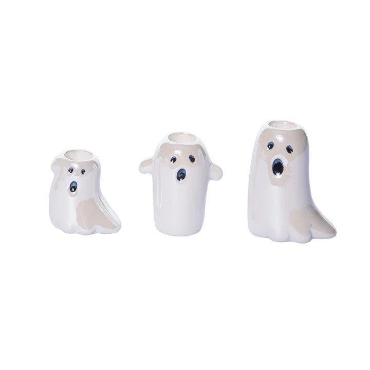 Three white taper candles in ghost-shaped holders with painted faces, shown on a plain white background.