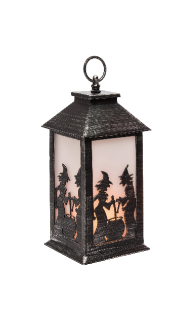 A black metal lantern with a hanging loop and a cutout silhouette of three witches riding broomsticks against a warm orange glow, shown on a plain white background.
