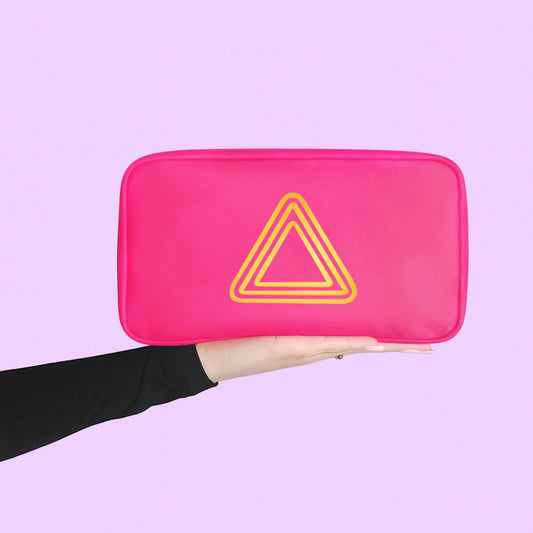 A hot pink car emergency kit rectangular zippered pouch with rounded corners and a yellow outlined triangle logo on the front, held in a person's hand against a solid lavender background.