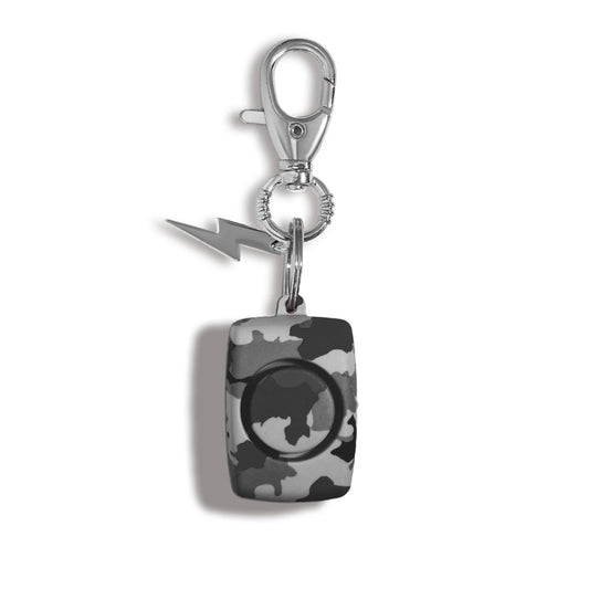A rectangular self-defense safety alarm keychain featuring a gray and black camouflage pattern, a circular button on the front, a silver metal clasp, and a small lightning bolt charm, shown on a white background with a soft drop shadow.