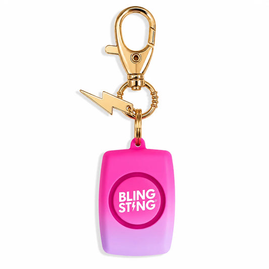 A pink and purple gradient personal safety keychain featuring a gold clasp, a gold lightning bolt charm, and a round button with the text 'BLING STING' in white, set against a plain white background.