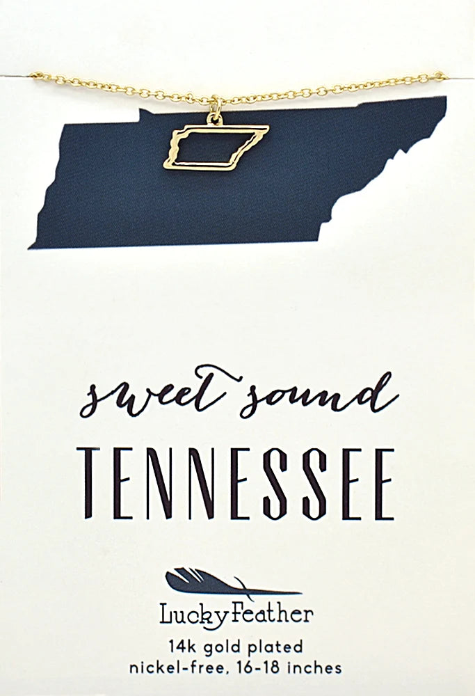 A gold necklace with a Tennessee state outline pendant is displayed on a white card. The card features a dark blue silhouette of Tennessee and the text 'sweet sound TENNESSEE' along with the Lucky Feather brand name and product details.