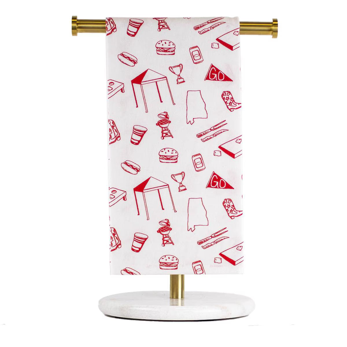 A white kitchen towel with a red line-art food and party pattern, hanging from a gold metal rod on a white and gold stand against a white background.  University of Alabama, Tuscaloosa, Crimson Tide, Tailgate football tea towel.