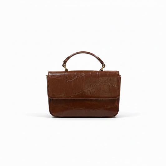 A brown leather handbag with a crocodile-embossed texture on the front flap and a glossy finish on the lower body, featuring a top handle and gold-tone hardware, set against a plain white background.
